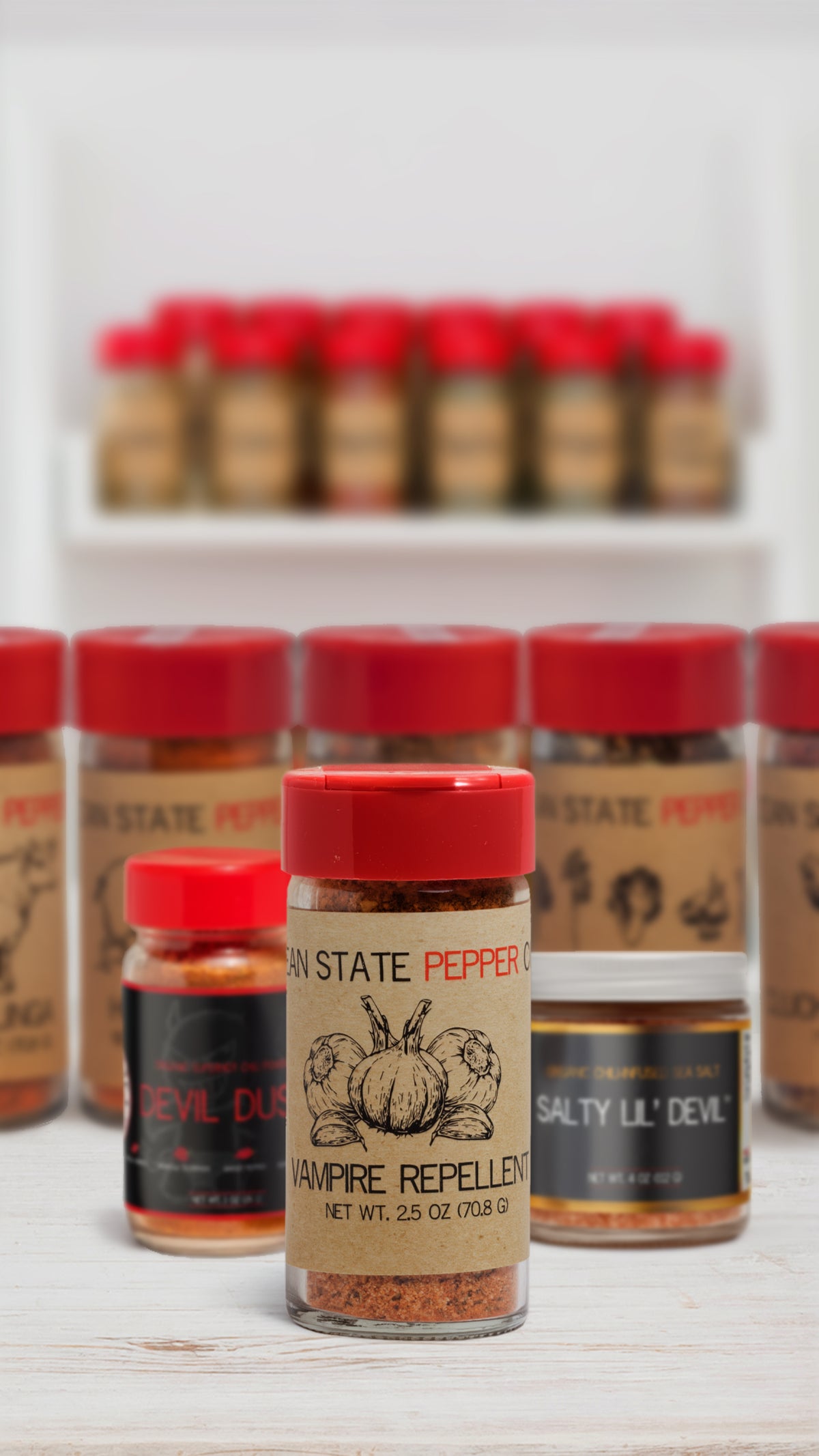 Assorted spice jars with red lids on a white surface, with more jars in the background.
